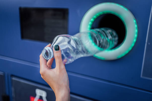 Woman throwing plastics bottle into trash bin for plastic waste.