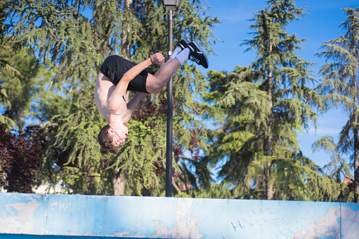 young male athlete doing parkour jumps and acrobatic exercises in the urban area of a city category urban gymnastics