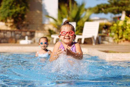 Portrait of a two Cute Little Girl Having Fun in the Pool. Sisters with Pleasure Spending Time Together n the Beach Resort. Happy Summer Vacation.