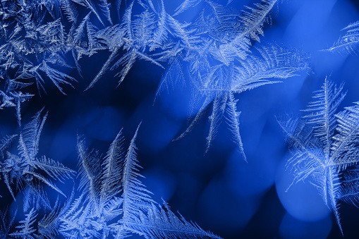 Beautiful frost pattern on a window in blue tones. Can be used as a winter / holiday background.