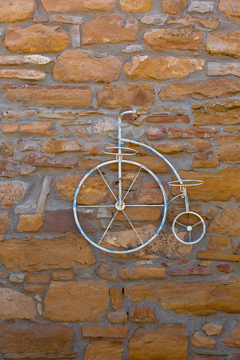 Decorative antique bicycle isolated on brown stone wall background. Bicycle, decoration, retro and vintage style concepts. Vertical close-up.