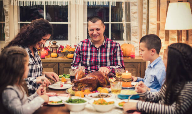 自宅で伝統的な感謝祭のディナーを持つ家族 - 6 11 months ストックフォトと画像