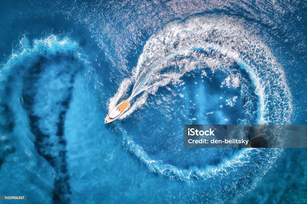 Aerial view of the speed boat in transparent blue water at sunset in summer. Top view from drone of fast floating yacht in mediterranean sea. Tropical colorful landscape with motorboat. Extreme Motorboat Stock Photo