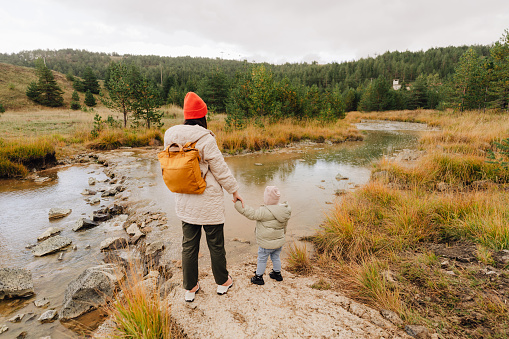 Photo of mother and daughter enjoying together by the stream on an autumn day