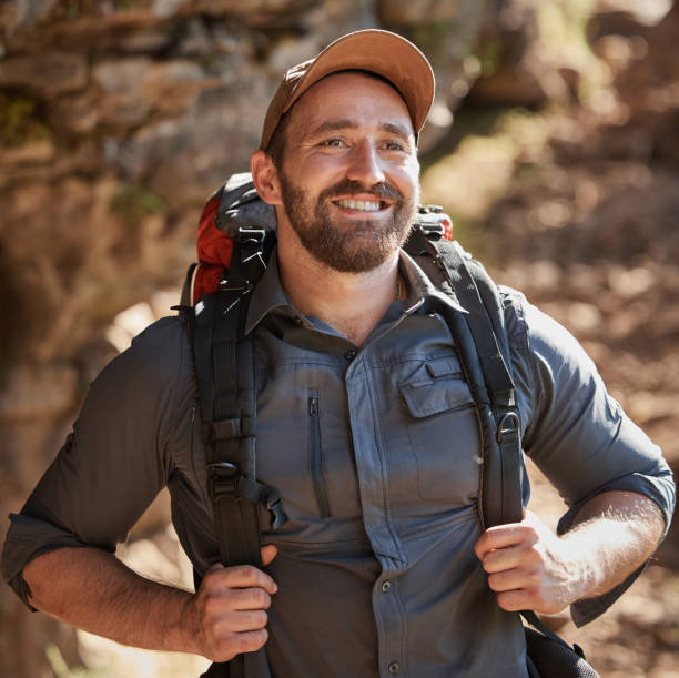 istock Happy caucasian man with beard carrying a backpack and hiking alone in the mountains during the day. Smiling fit and active man enjoying nature while exercising and exploring. Staying active on adventures 1432959171