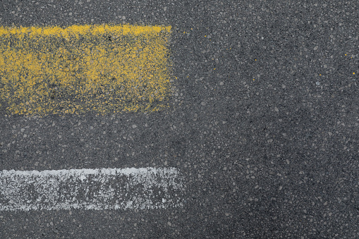 White and yellow asphalt mark, white and yellow line on a street or road, texture as a background with space for text