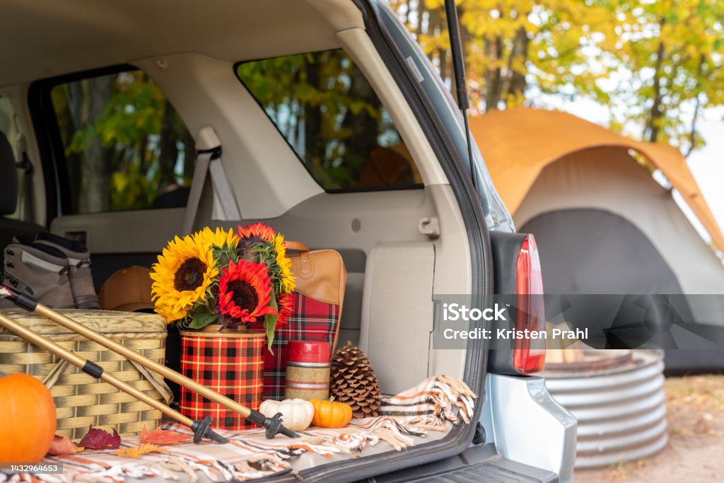 Open tailgate with vintage picnic items at a campsite in autumn Open tailgate with hiking and picnic items and tent in blurred background Car Stock Photo