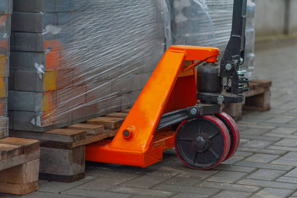 Old orange manual hand pallet trucks. Close up wheel of hydraulic hand pallet truck Old orange manual hand pallet trucks. Close up wheel of hydraulic hand pallet truck. rusty old wagon detail stock pictures, royalty-free photos & images