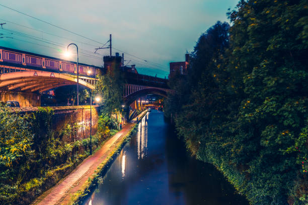 czerwony historyczny most biegnący nocą nad kanałem castlefield w manchesterze - railroad crossing bridge river nautical vessel zdjęcia i obrazy z banku zdjęć