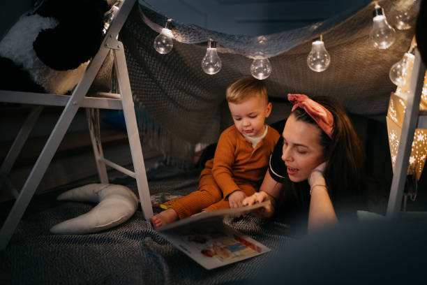 istock Mother and son with a book and a flashlight before going to bed 1432970184