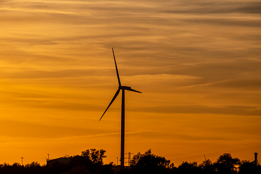 the silhouette of a pinwheel at sunset, against an orange sky