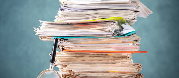 istock Pile of papers and a magnifying glass 1432973752