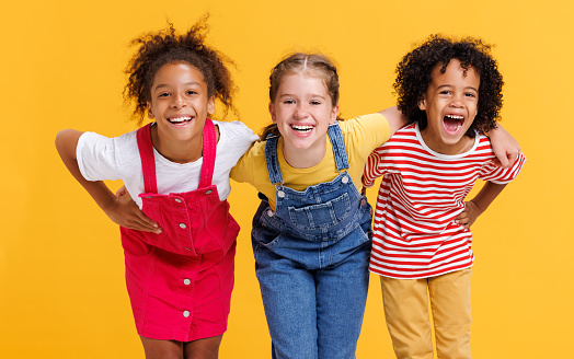 Group of cheerful happy multinational children on a colored yellow background