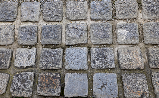 Closeup of ancient square paving stones with gaps in between providing texture.