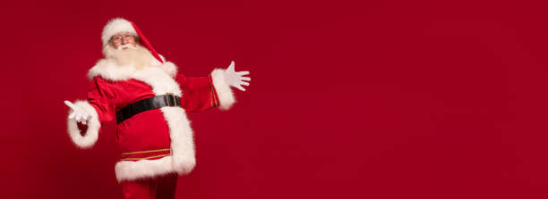 istock Santa Claus posing with open hands and smile on a red studio background. Merry Christmas and Happy New Year! Copy space. Xmas sale, discount concept. 1432975144