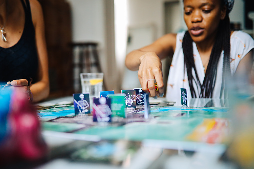 Female friends playing fantasy role playing games on the table. Close up on the one of the characters on the playfield.