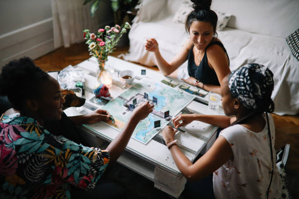 grupo de amigos jogando um jogo de tabuleiro em casa - leisure games dice indoors table - fotografias e filmes do acervo