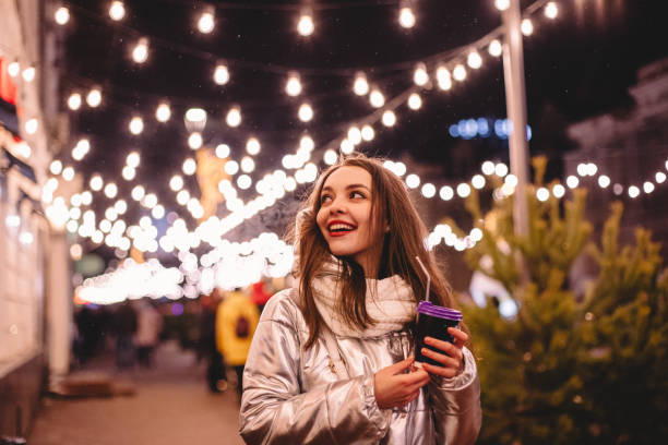 fröhliche glückliche junge frau, die nachts in den weihnachtsferien in der stadtstraße spazieren geht - walking at night stock-fotos und bilder