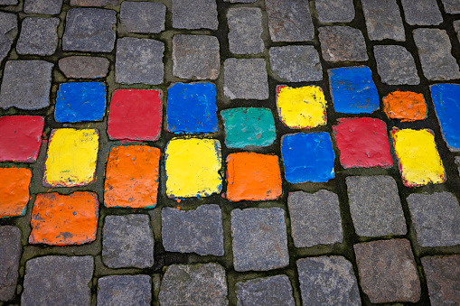 Colored stones on the cobble alleys and footpaths of Passau, Germany lead tourists and locals to various artist shops. The stones were painted to create interest and increase business for the local artists in Hollglasse Artists Alley.