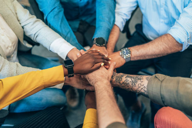 Teamwork Unrecognizable multi ethnic business team holding their hands together. Modern business team holding hands like successful team. camaraderie stock pictures, royalty-free photos & images