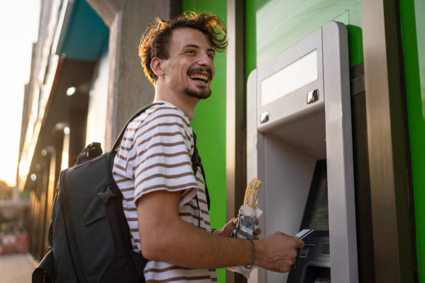 side view man use ATM machine to withdraw money with credit card stock photo