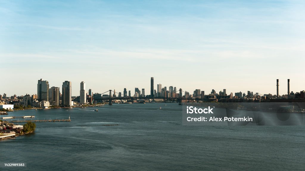 East River view with Williamsburg Bridge over the river with Manhattan and Williamsburg, Brooklyn at the distance. East River with Williamsburg Bridge and distant view of Manhattan and Williamsburg, Brooklyn behind. Aerial View Stock Photo
