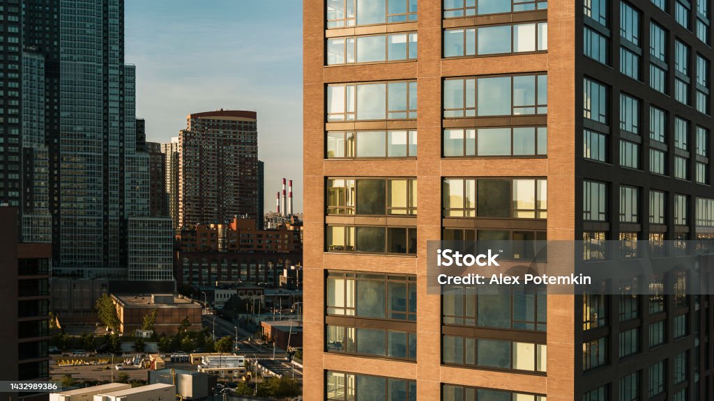 New residential building in Hunters Point, Queens, with the view of the smokestacks of power plant in Astoria, Queens, in the backdrop. Residential area with new modern condos in Hunters Point, Long Island, Queens. Apartment Stock Photo