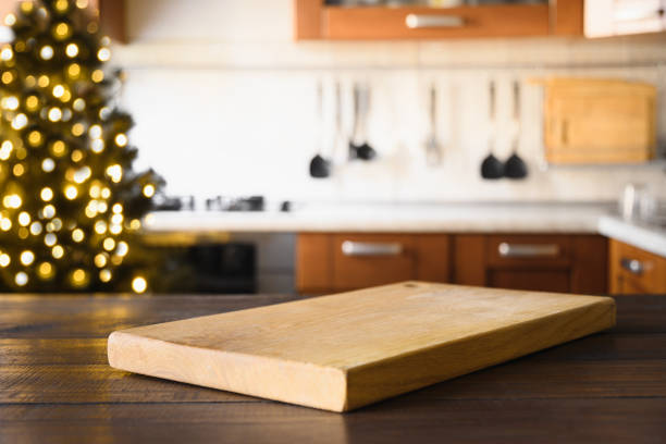 istock Wooden tabletop with cutting board and blurred kitchen with Christmas tree. Background for display or montage your products. 1432993858