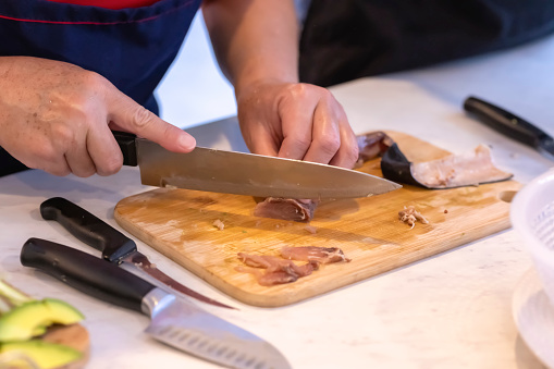 Hands cutting fish to make sashimi.