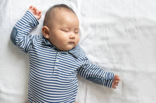 istock A baby boy in a striped shirt is sleeping in bed. 1433005319