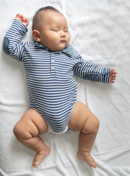 istock A baby boy in a striped shirt is sleeping in bed. 1433005320