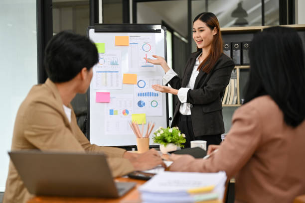 Bright and professional Asian female financial analyst presenting data in the meeting stock photo