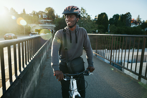An adult African American man enjoys a bicycle ride on a brisk and sunny autumn day in the Pacific Northwest.   Shot in Seattle, Washington, USA.
