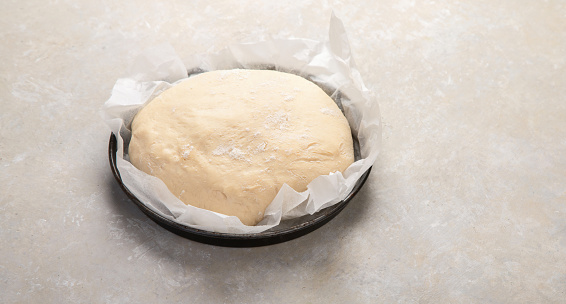 Raw dough pastry in a bowl on neutral background. Homemade bio food concept.