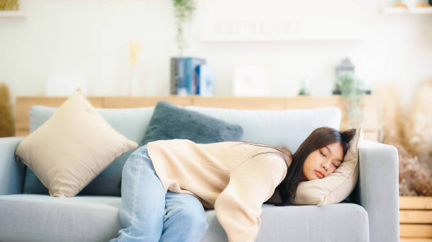 istock Asian woman resting at home on couch, feeling exhausted after work, lacking energy, or overworked, too tired, and lacking motivation 1433015450