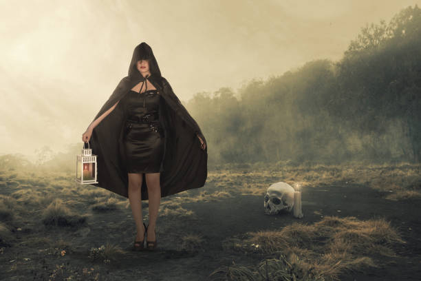 Asian witch woman with a black cloak holding a lantern standing on the field with the dramatic scene background