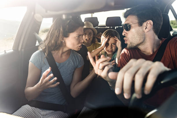 Frustrated parents arguing during trip by a car. Angry parents arguing while traveling with their displeased kids in car. The view is through windshield. arguing couple divorce family stock pictures, royalty-free photos & images