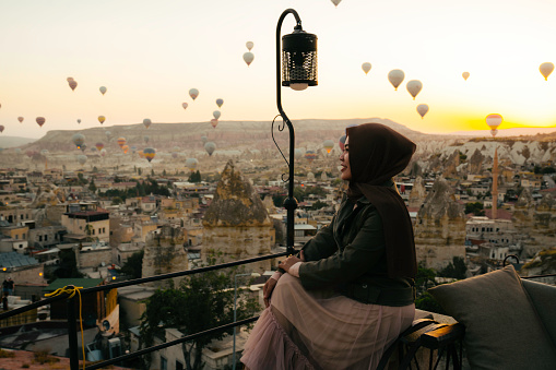 young muslim  woman looking view  of hot air balloon in cappadocia