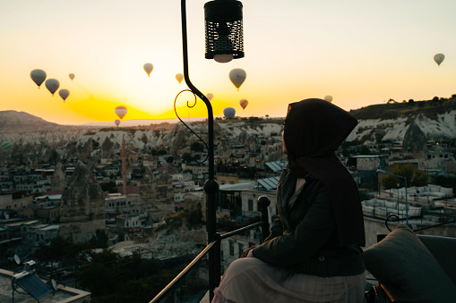 young muslim  woman looking view  of hot air balloon in cappadocia