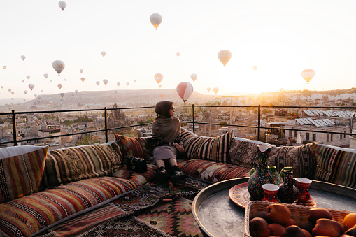 Cappadocia Turkey during sunrise, a mature couple of men and woman on vacation in the hills of Goreme Cappadocia Turkey, men and woman looking sunrise with hot air balloons in Cappadocia Turkey