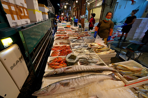 Fishmonger at work with display of fresh fish at old market in Cadiz Spain 03 August 2023