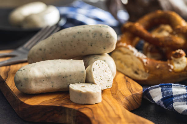Traditional Bavarian white sausages on cutting board and pretzels. Traditional Bavarian white sausages on the cutting board and pretzels. weisswurst photos stock pictures, royalty-free photos & images