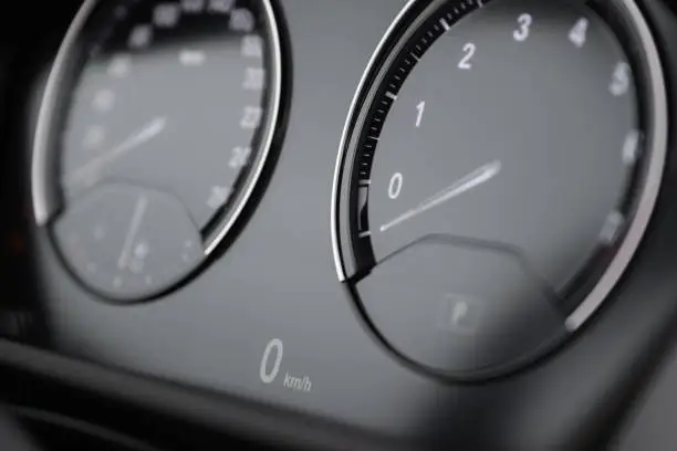 Close up of a car dashboard with LCD digital speedometer readout showing 0 km/h. Selective focus.