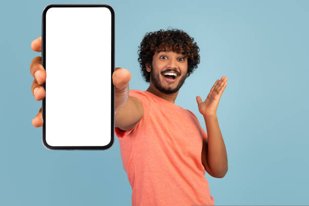 istock Emotional curly indian man showing cell phone with empty screen 1433033947