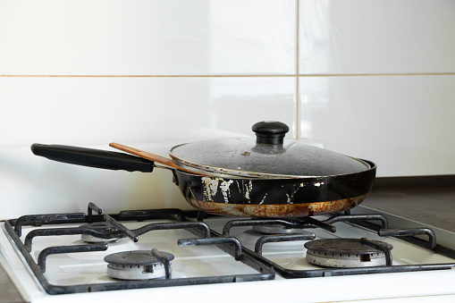 Gas stove and dirty frying pan in the kitchen in an apartment in Ukraine, kitchen furniture and appliances, kitchen interior