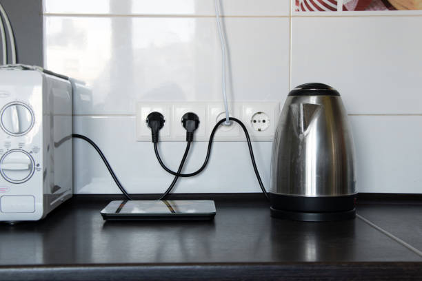 Kitchen and electric kettle on the table near the socket against the background of white tiles, kitchen appliances, kitchen furniture stock photo