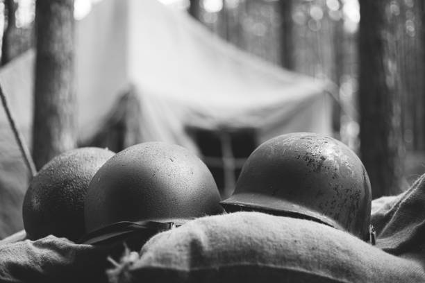 Metal Helmets Of United States Army Infantry Soldier At World War II. Helmets Near Camping Tent In Forest Camp. black and white photography. stock photo
