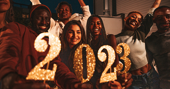 Multi ethnic group of friends celebrating 2023 New Year's Day.