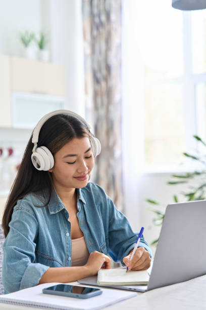 istock Teen asian student making notes in notebook during online lesson webinar 1433039779