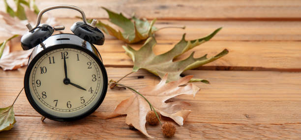 istock Daylight Saving Time, Fall Back. Black clock and autumn leaves on wood 1433040763